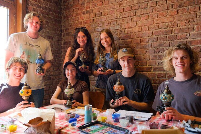 Un grupo de personas sosteniendo adornos en una mesa, con un muro de ladrillo al fondo. 1