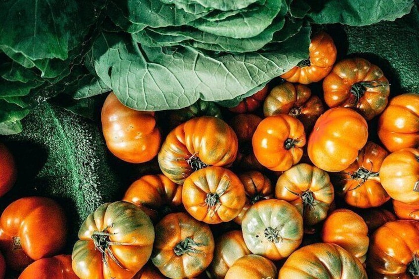 Ein Haufen Tomaten mit grünen Blättern im Hintergrund. 2
