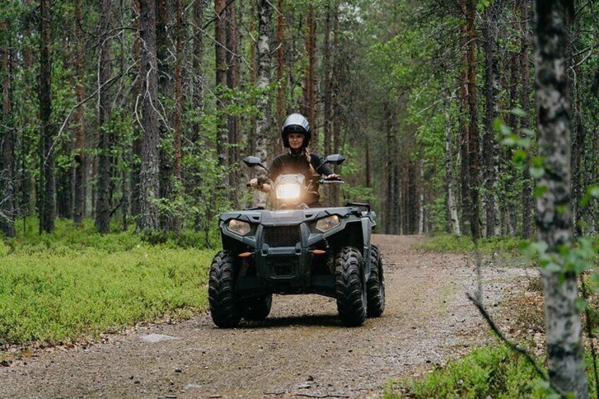 Eine Person fährt mit einem Geländefahrzeug auf einem Waldweg. 3