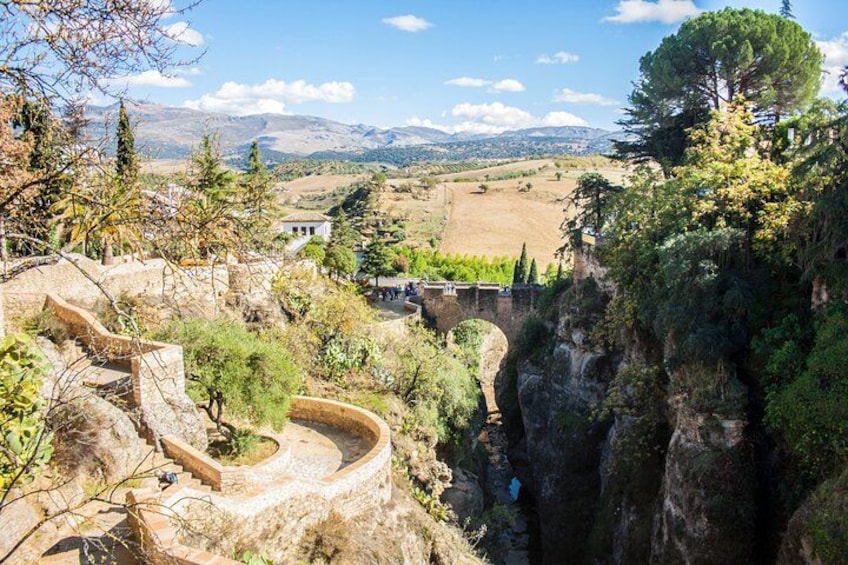 A stone staircase descending a steep cliff, a bridge, and a vineyard in the valley below. 2