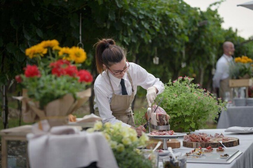 Une personne prépare des aliments à l’extérieur, avec des fleurs et une table dressée pour un repas. 4