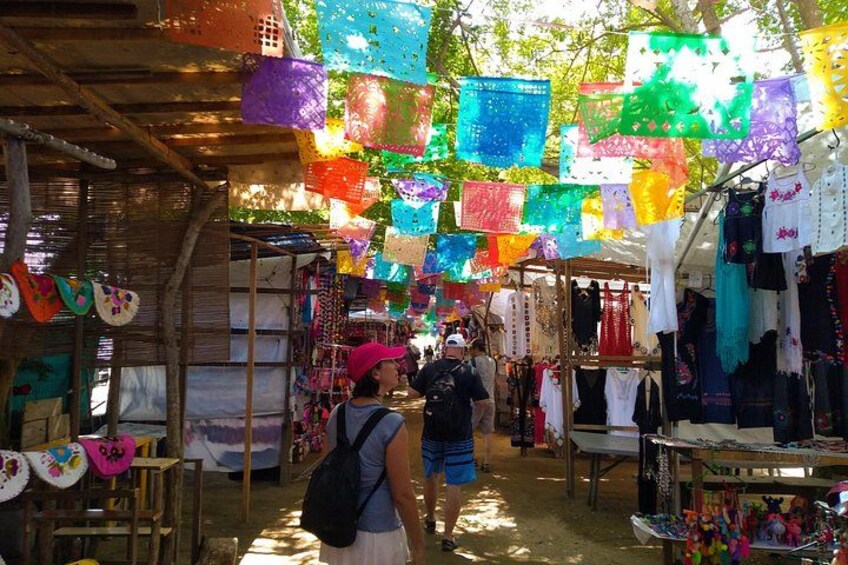 A market with colorful hanging decorations and various stalls selling clothes and accessories. 1