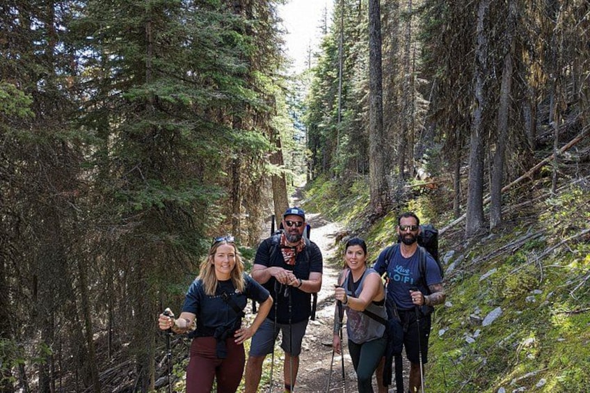 A group of people hiking on a forest trail surrounded by tall trees. 2