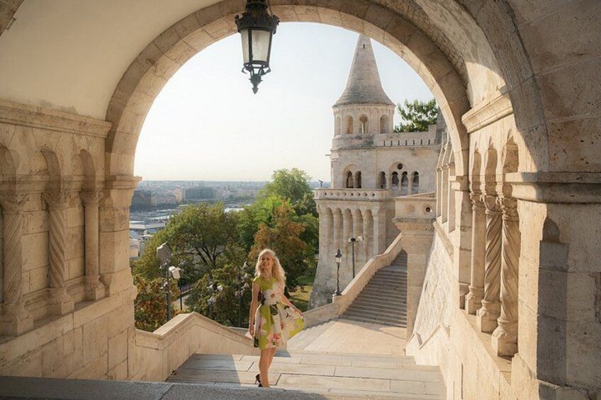 A woman descending a stone staircase with an arched entrance, leading to a tower with a conical roof. 3
