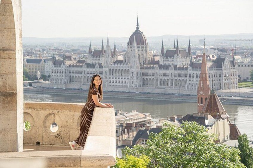 A person standing on a balcony overlooking a cityscape with a prominent building with a dome and spires. 2