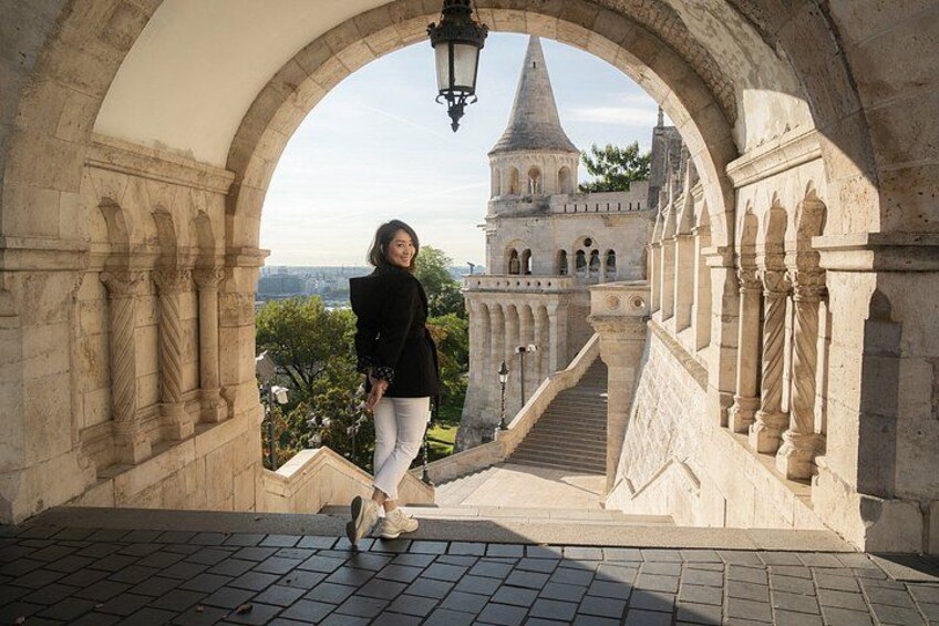 A person standing in an archway overlooking a historic building with a tower. 5