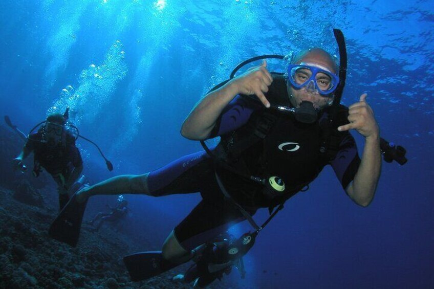 Two scuba divers underwater with one pointing to the camera. 2