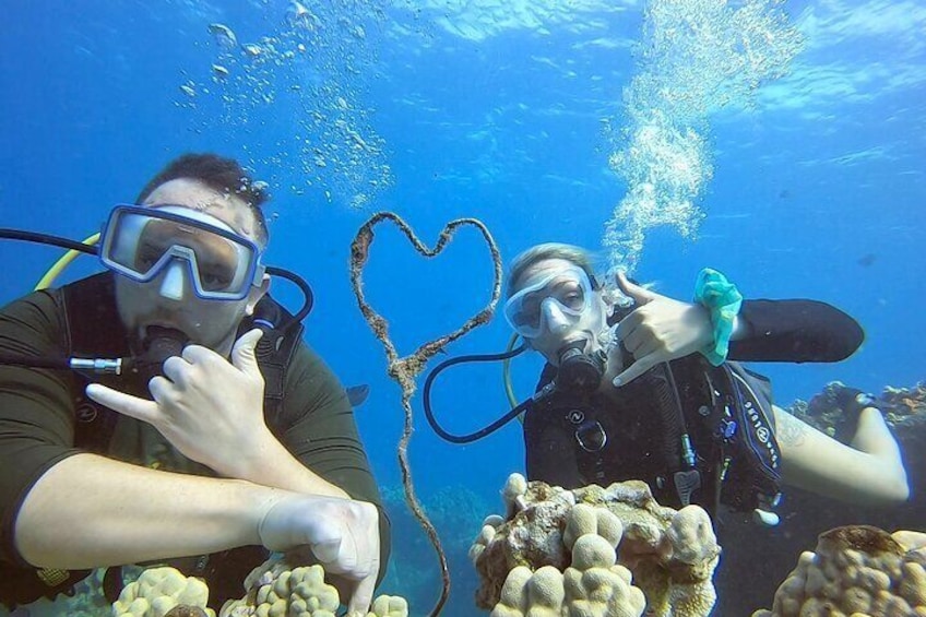 Two divers underwater with coral formations and a heart-shaped structure. 1