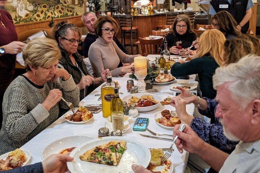 Eine Gruppe von Menschen speist in einem Restaurant, auf dem Tisch befinden sich verschiedene Gerichte und Getränke. 1