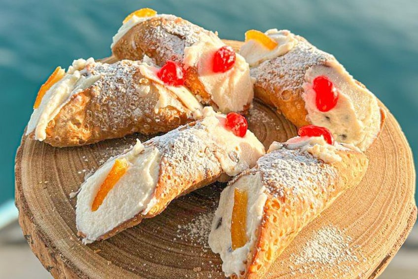 Cannoli med flødefyld og stykker af rød frugt på en træplade. 2