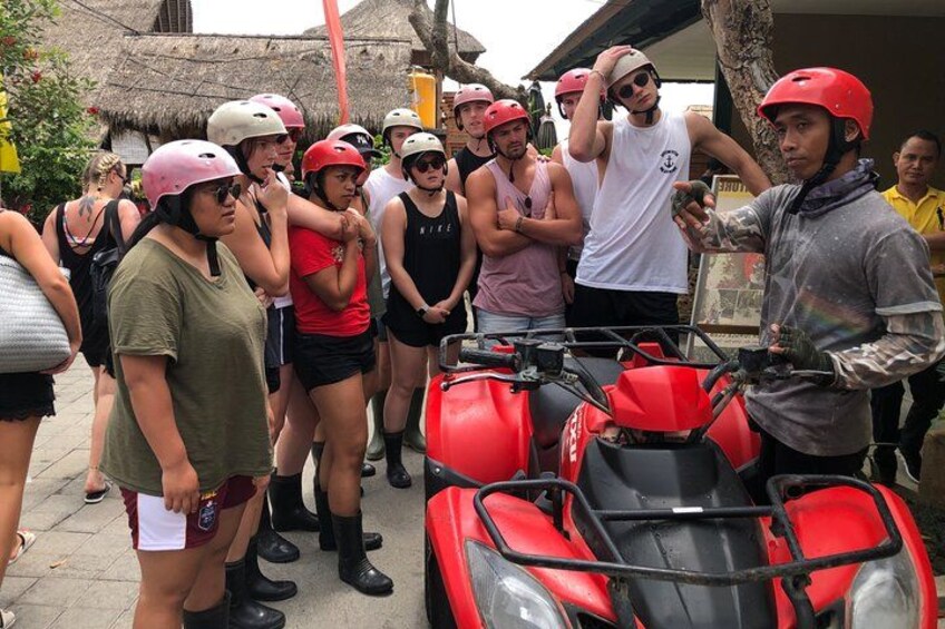 A group of people wearing helmets and standing near red ATVs. 3