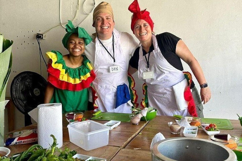 Tres personas con vestuario llamativo sentadas a una mesa con comida y utensilios de cocina. 5