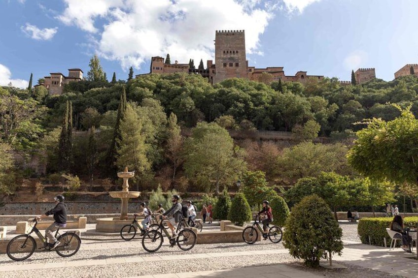 Ein Blick vom Hügel auf ein Schloss, Radfahrer auf einem Weg und eine Springbrunnen. 1