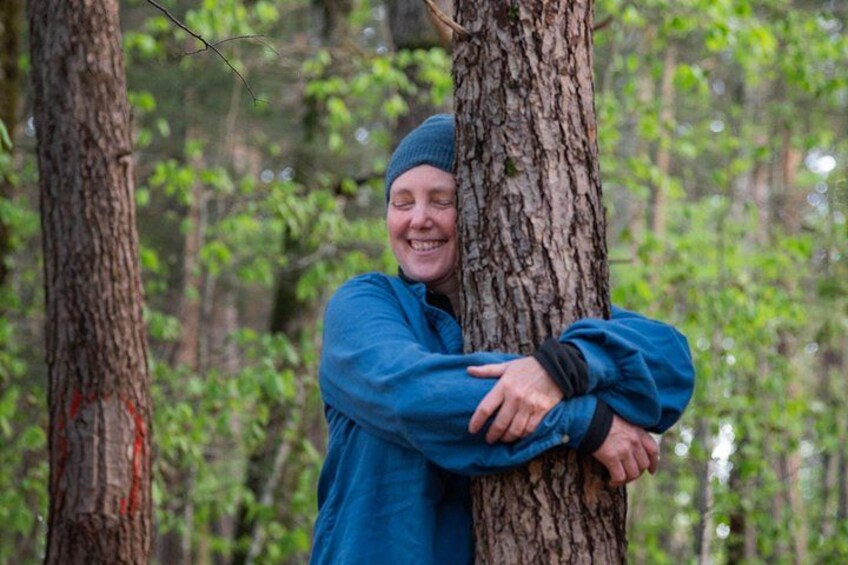 A person hugging a tree in a forest. 1