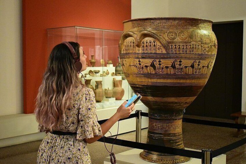 A person examining a large ancient vase with intricate designs. 4