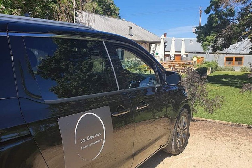 En svart skåpbil stod parkerad på en grusuppfart, och på den satt en skylt med texten ”Gold Class Tours”. 1