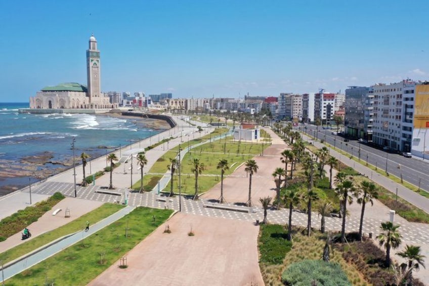 A coastal promenade with palm trees, a beach, and a mosque with a minaret. 4