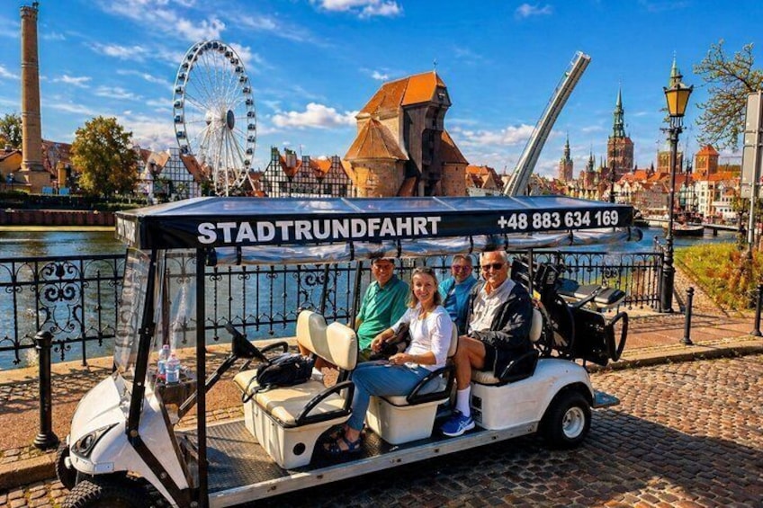 En guidet rundtur i en turistbus, et pariserhjul og historisk arkitektur i baggrunden. 2