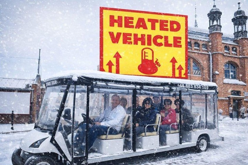 A heated vehicle with passengers, a snow-covered environment, and a building with a clock tower in the background. 3
