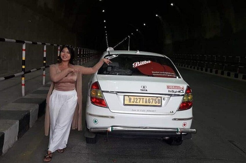 Een witte auto geparkeerd in een tunnel, met een vrouw ernaast staand. 5