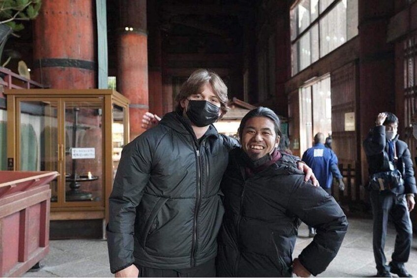 Two people standing in an indoor space with large windows and wooden beams. 4