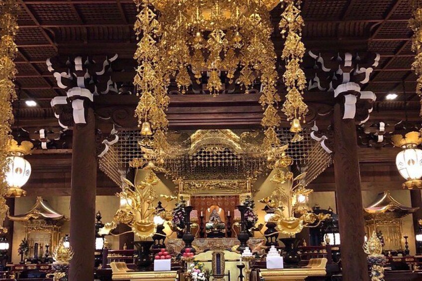 A temple interior with ornate golden decorations, a central altar, and traditional architecture. 2