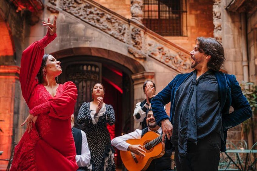 A person in a red dress dancing, another person in a blue jacket playing a guitar, and a building with ornate architecture in the background. 3