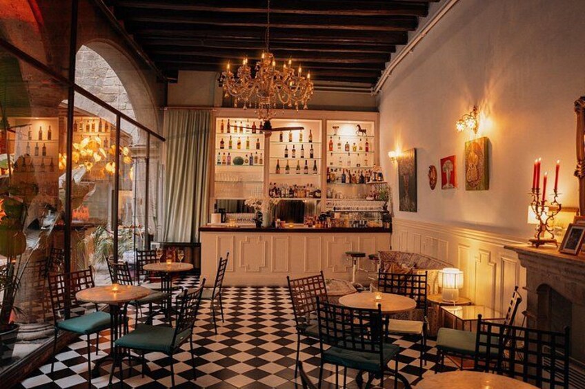 Un bar con pavimento a scacchi, sgabelli da bar e un lampadario. 3