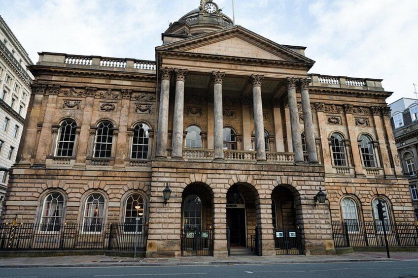 A large, historic building with columns, arched windows, and a clock tower. 2