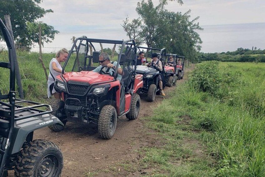 Un gruppo di persone su veicoli fuoristrada rossi che percorrono un sentiero sterrato in zona rurale. 2