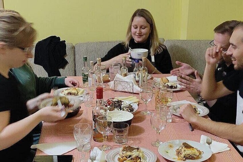 A group of people dining at a table with various dishes, glasses, and bottles. 4