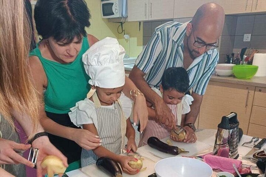 Una famiglia prepara il cibo in cucina, con un forno a microonde, una ciotola e diversi utensili da cucina. 3