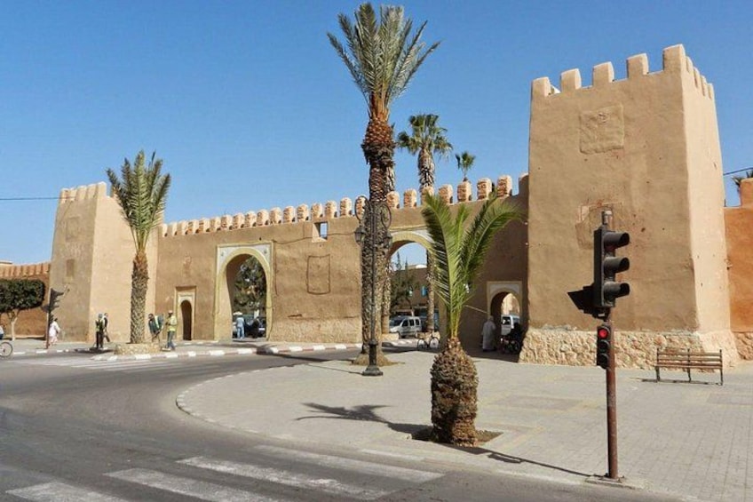 A historic fort with arched gateways, palm trees, and a traffic light. 3