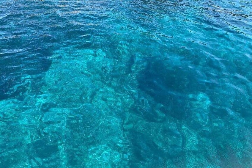 Agua azul cristalina con rocas visibles bajo el agua y vida marina. 2