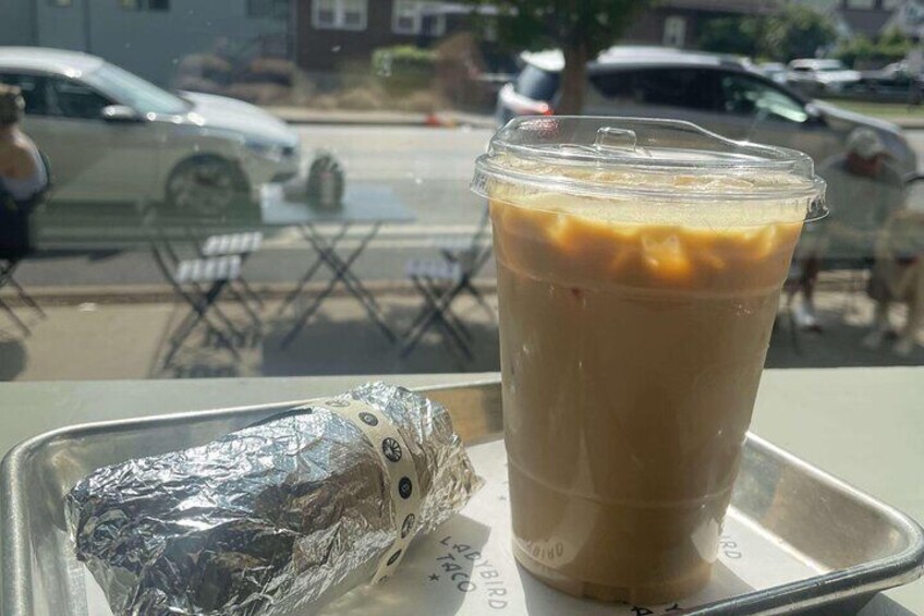 A beverage in a clear plastic cup with a foil-wrapped item beside it, on a tray. 4