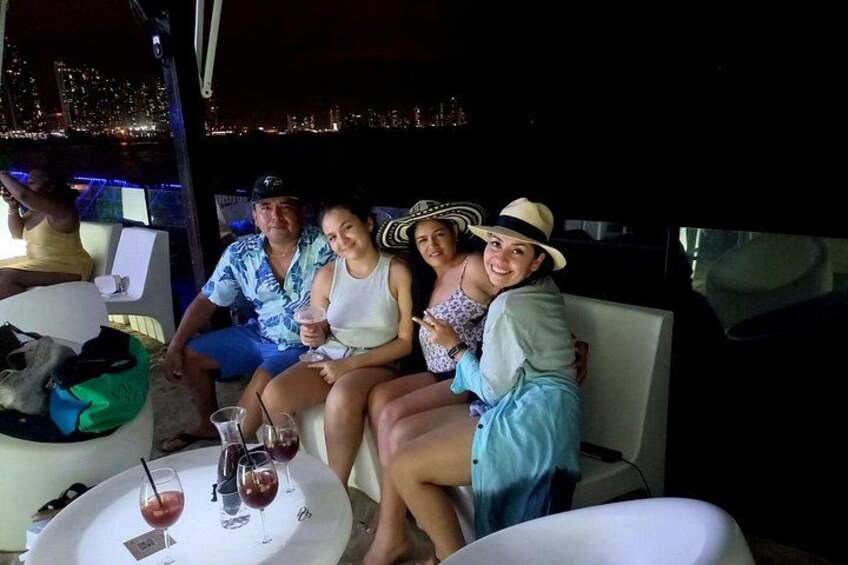 Un grupo de personas sentadas en un bote con un paisaje urbano al fondo. 1