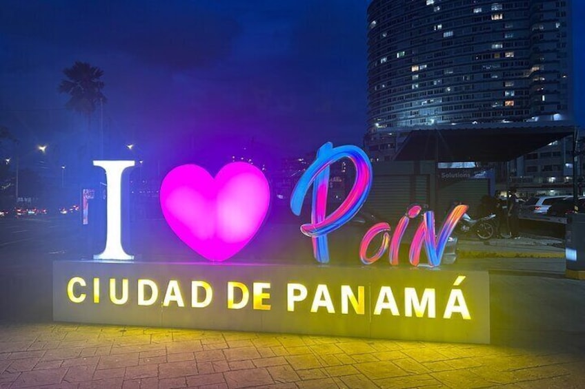 Un letrero nocturno con 'I ♥ Poin Ciudad de Panamá' iluminado con luces de neón. 1
