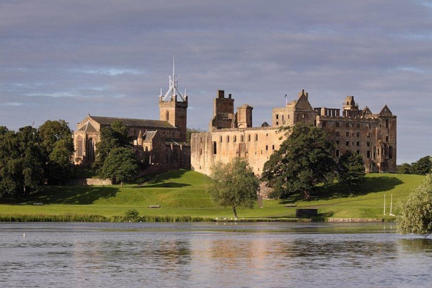 Un castillo histórico con una iglesia, rodeado por un lago y vegetación. 1