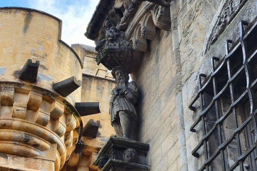 Un edificio de piedra con una estatua de león y un ventanal con barrotes. 4