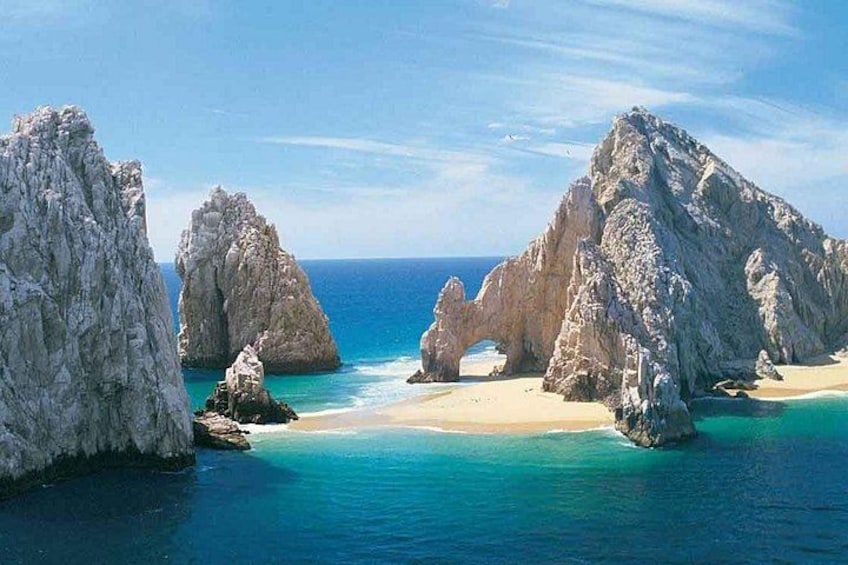 A coastal landscape with rocky formations, clear turquoise waters, and a sandy beach. 3