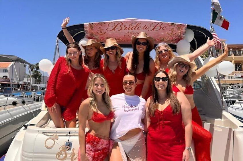 A group of people on a boat with a banner that reads 'Bride to Be.' 1