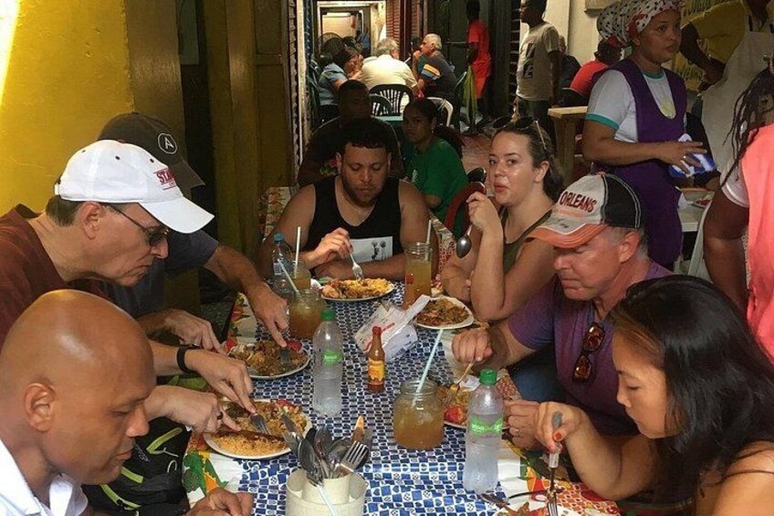 Eine Gruppe von Menschen speist an einem Tisch mit Essen und Getränken. 3