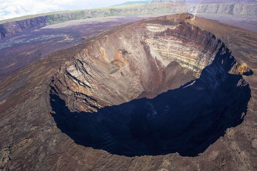 A large, deep pit with steep walls, surrounded by flat terrain and sparse vegetation. 2