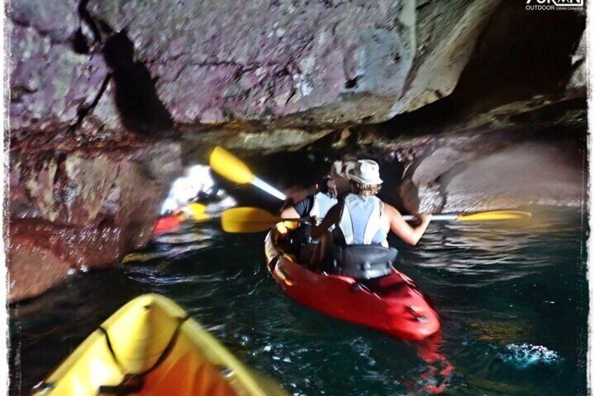 Una persona remando en kayak rojo bajo una formación rocosa. 2