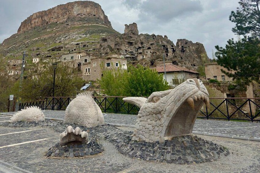 A rocky landscape with a large mountain in the background and a stone sculpture in the foreground. 1