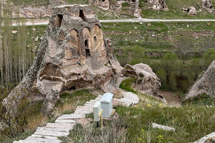 A rock formation with carved niches, a stone staircase, and a utility box. 4