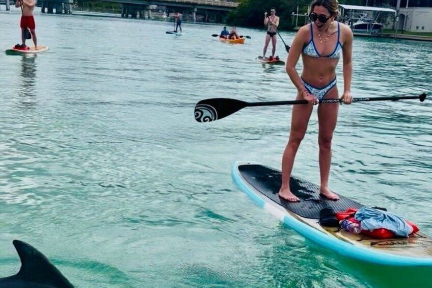 A person paddleboarding on a body of water with other people in the background. 3