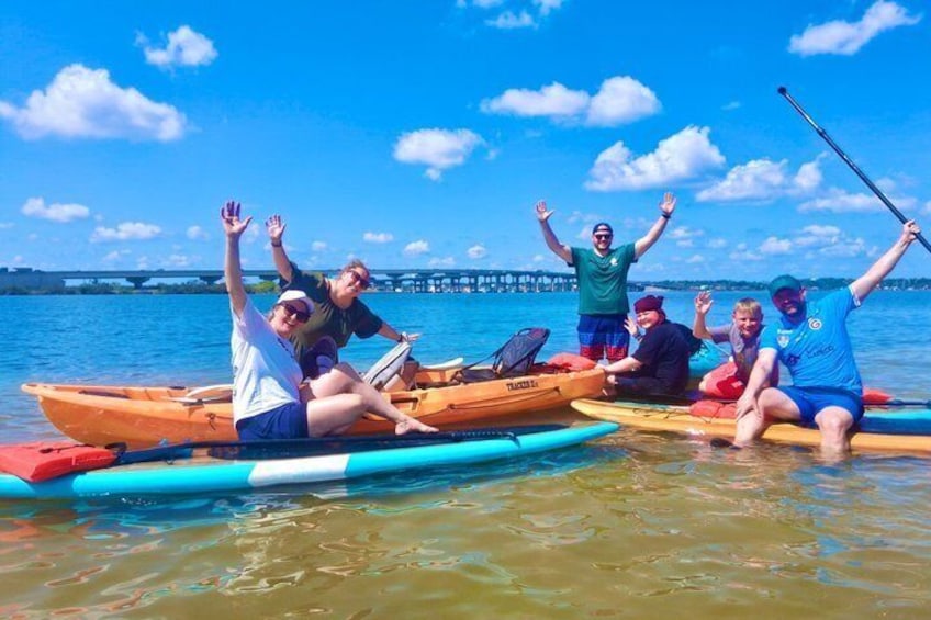 People on paddleboards in a body of water with a bridge in the background. 2