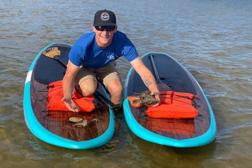 A person sitting on a paddleboard with two life jackets and a paddle. 5