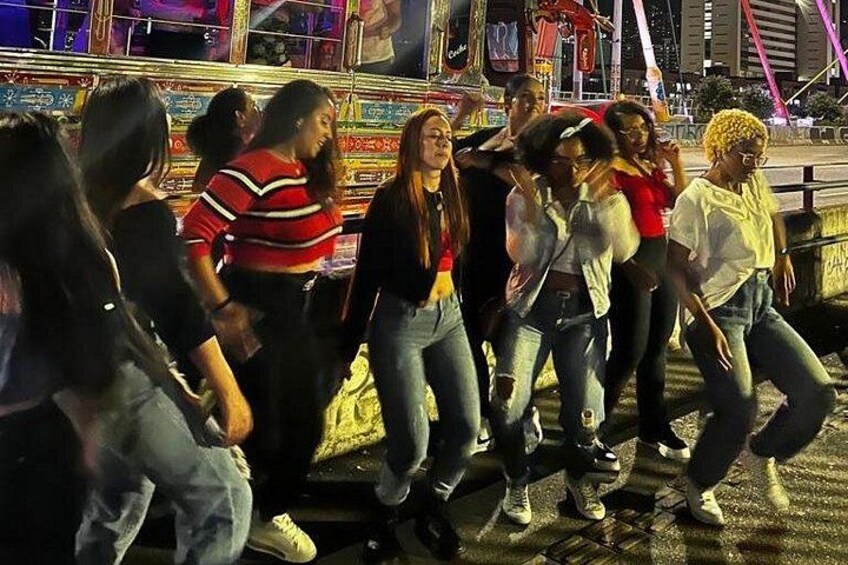 A group of people dancing in an urban setting at night. 2